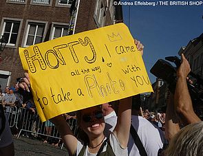 Junge Frau mit einem Plakat auf dem steht: Harry, I came all the way to take a photo with you.